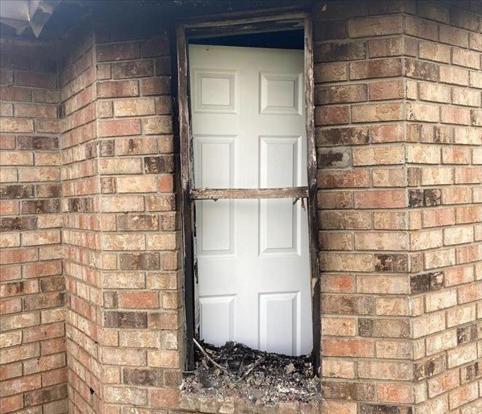 Structure with charred window blocked by a white door