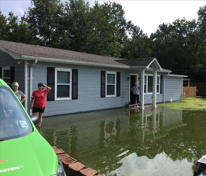 People standing in front of a flooded home