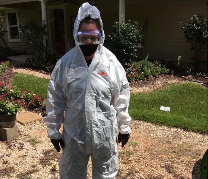 SERVPRO tech, donned in PPE, stanading in front of home