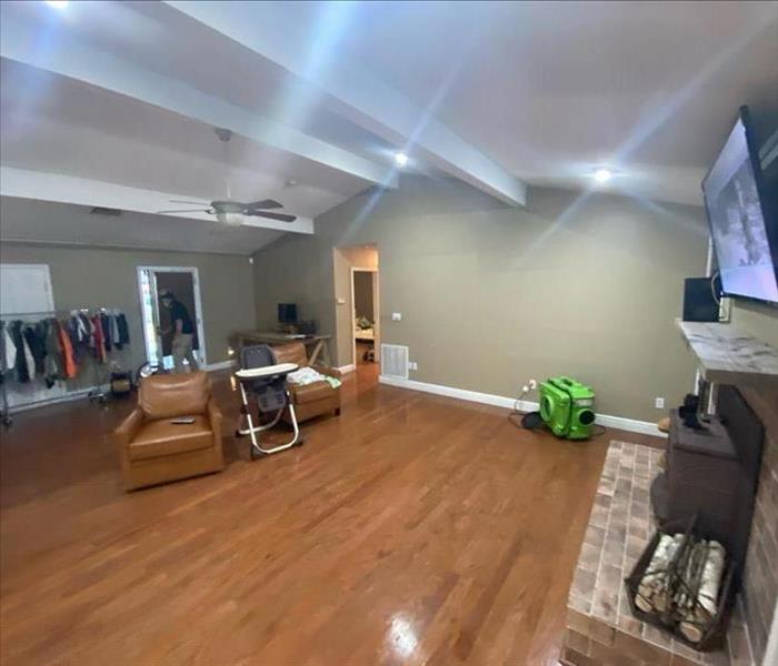 Room with SERVPRO air scrubber by chairs and fireplace on hardwood floor 