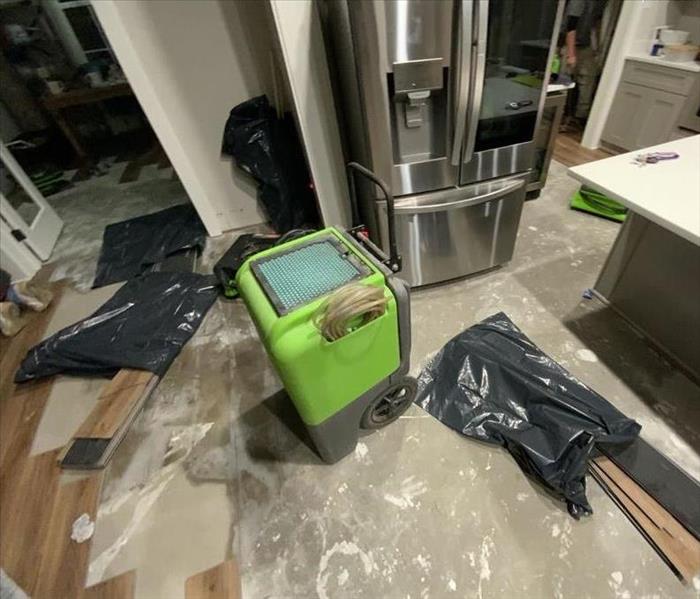 Dehumidifier on a partially removed laminate floor with water damage underneath