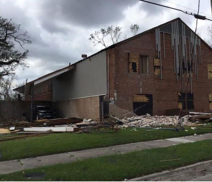 Building with boarded up windows and debris in front of it