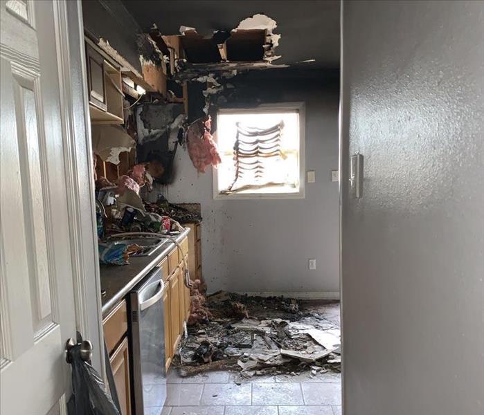 Kitchen fire damage collapsed ceiling and overhead cabinets, leaving debris on floor and counters and warping blinds