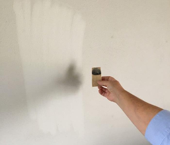 SERVPRO tech holding chem sponge by smoke damaged wall