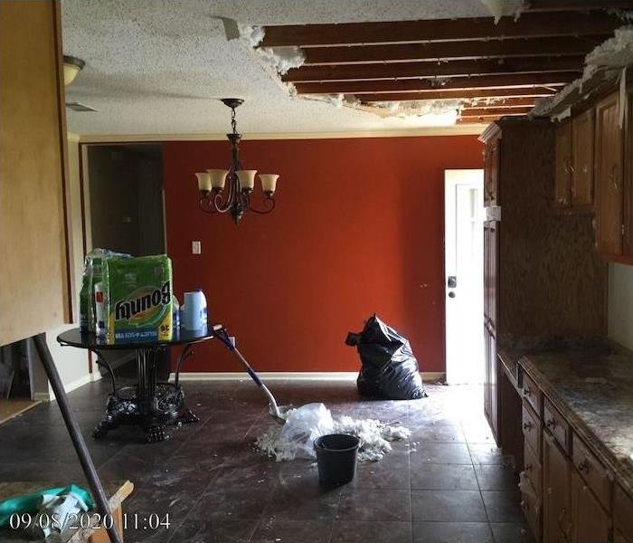 Room with falling ceiling and mop on wet tile floor