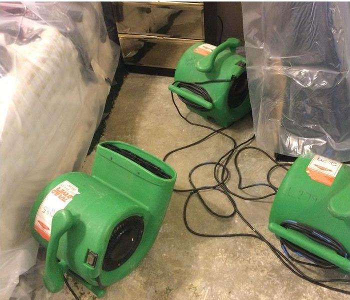 SERVPRO restoration equipment being used in water damaged room; flooring removed