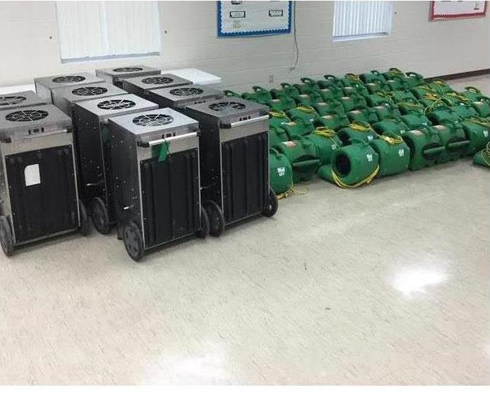 SERVPRO equipment lined up and down a wall in a commercial business. 