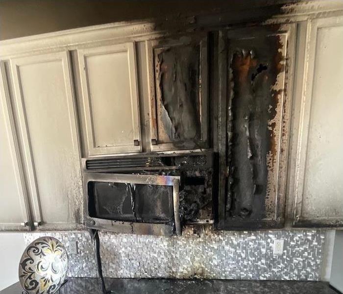 Kitchen cabinets and microwave with fire damage