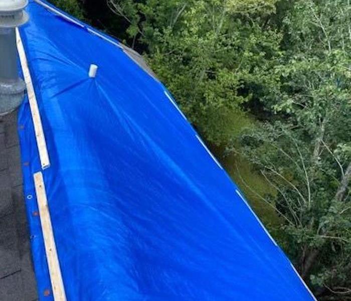 A roof with a blue tarp over it. 